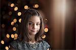 Portrait of girl in front of christmas tree looking at camera smiling