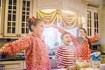 Children in kitchen wearing pyjamas arms open looking away smiling