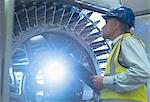 Supervisor with clipboard examining machinery in printing plant