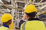 Workers discussing printing press conveyor belts overhead