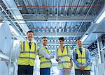 Portrait smiling workers in reflective clothing in factory