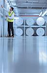 Worker examining large paper spools in printing plant