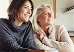 Smiling mother and daughter in sweaters looking away