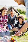 Family barbecuing at sunny campsite