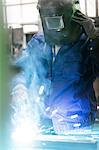 Welder in protective workwear working in factory