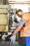 Worker in protective workwear operating machinery in factory