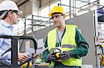 Engineer and worker in protective workwear talking in factory