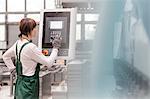 Worker at control panel operating machinery in factory