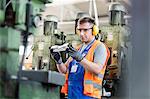 Worker in protective workwear examining part in factory