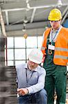 Engineer explaining steel parts to worker in factory