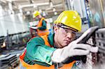 Focused worker examining steel part in factory