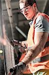 Focused worker holding steel part in factory