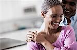 An affectionate mature African American couple, with their arms around each other in their home.