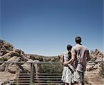 A man and woman on the terrace of an eco house, looking over the rocky landscape
