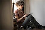 Loft living. A man sitting by a window using a digital tablet.