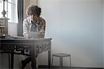 Loft living. A man sitting at a table by a window using a digital tablet.