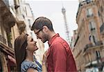 A couple, a man and woman looking into each other's eyes on a city street.