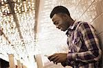 A man in a brightly lit space, a casino entrance, checking his smart phone.