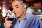 Man with grey hair drinking wine