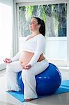 Pregnant woman sitting with eyes closed on exercise ball