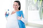 Pregnant woman holding exercise mat and water bottle