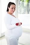 Pregnant focused woman lifting dumbbell