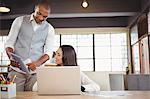 Man showing digital tablet to female colleague