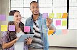 Woman holding tablet and looking at sticky note