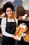 Pretty waitress showing tray of croissants