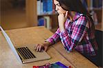 Concentrated female student using laptop in library