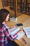 Concentrated female student writing in book at table