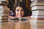 Happy female student leaning on book at table