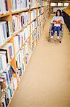 Disabled female student reading book on wheelchair