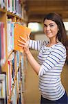 Confident female student selecting book