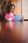 Pretty student using tablet in cafe