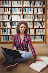 Pretty student in library using laptop