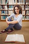 Pretty student in library smiling at camera