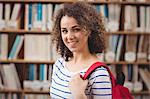 Pretty student in library smiling at camera