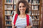 Pretty student in library smiling at camera