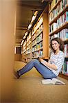 Pretty student in library sitting on the floor