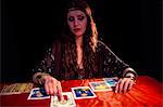 Fortune teller woman with eyes closed and pointing at tarot card