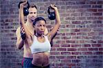 Woman lifting kettlebells with her trainer