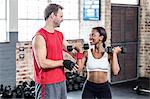 Smiling muscular couple lifting weight
