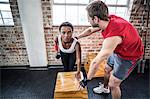Muscular woman lifting dumbbell with her trainer
