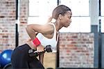 Muscular focused woman lifting dumbbell