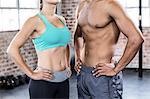 Fit couple with hands on the hips in crossfit gym