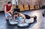 Male trainer assisting woman with push ups