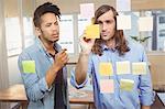 Businessman writing while colleague watching at sticky notes