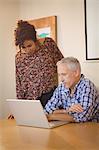 Creative businessman with colleague looking in laptop