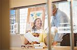 Businesswoman smiling while showing document to colleague